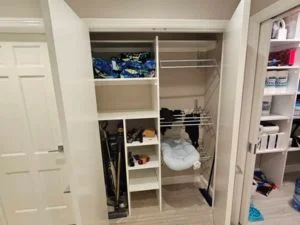 White closet organizer with shelves, cubbies, and hanging rod beside painted white trim and doors