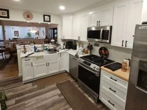 White painted kitchen cabinets with stainless steel appliances and wood-look countertop